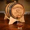 Custom engraved oak whiskey aging barrel pouring whiskey into glass on wooden table