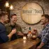 Custom Buffalo Trace style barrel head sign mounted in a rustic home bar with men enjoying whiskey and branded bottle on bar