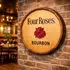 Four Roses bourbon barrel head wall sign mounted on brick wall in restaurant bar setting